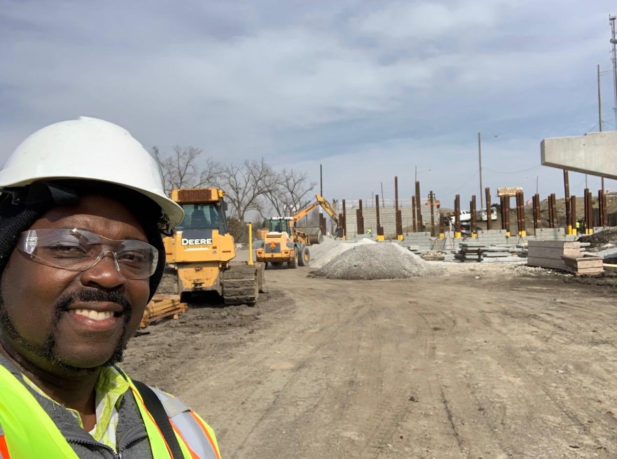 Civil works site with heavy equipment, excavation activity, and construction materials.