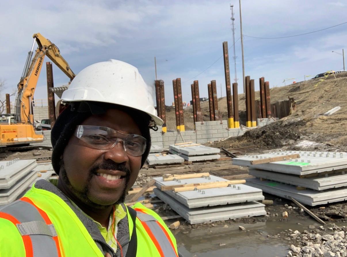 Civil works in progress with excavation equipment, precast elements, and site safety gear.