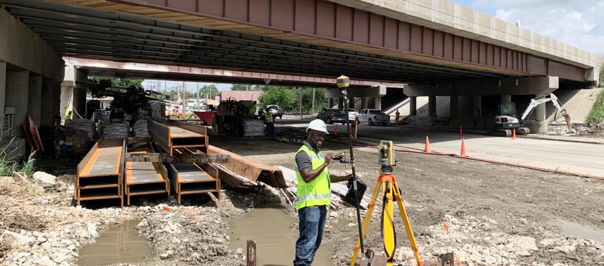 Surveying equipment and field engineering work beneath bridge infrastructure.